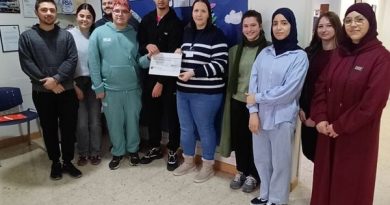 Miembros de la asociación AFEDABA Los Calatravos y alumnos posan en el local de la entidad durante la entrega de un cheque.